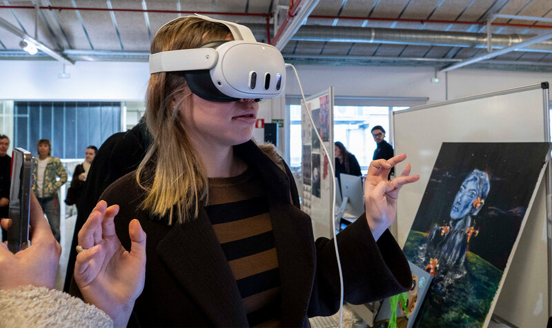 A young woman wearing virtual reality glasses at a graphic design exhibition