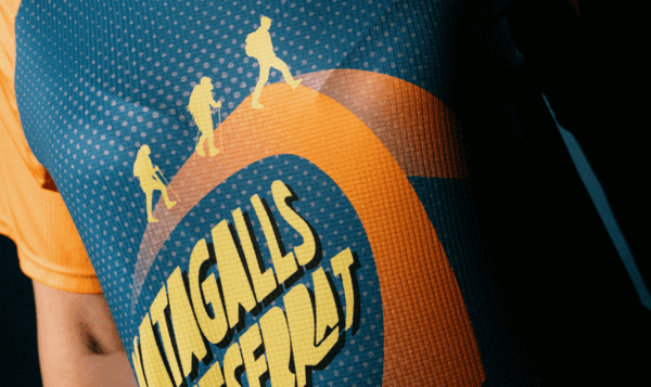 Close-up of a technical sports t-shirt with a graphic design of three hikers reaching the summit