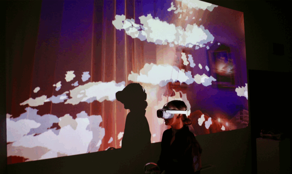 A person wearing virtual reality glasses in front of an interactive screen