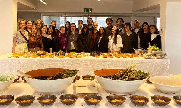 A group of people posing behind a long table with food